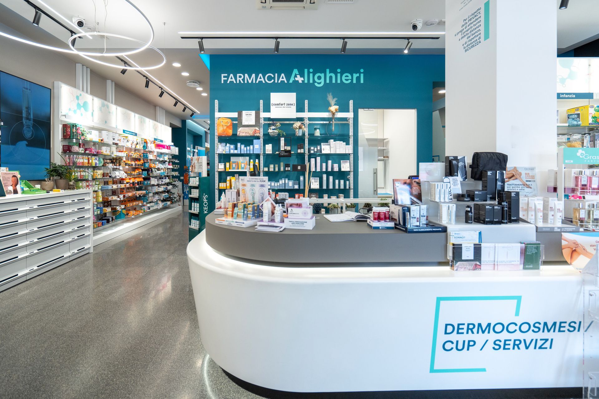 Luminoso interno della farmacia, moderna, con scaffali pieni di prodotti e un bancone bianco curvo.