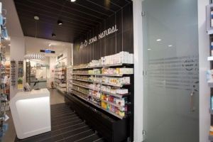 Una farmacia con muchos estantes y un mostrador.