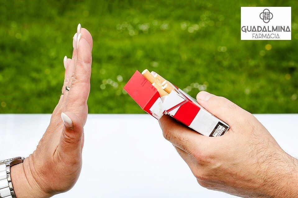 Una persona está haciendo una señal de pare mientras sostiene un paquete de cigarrillos.