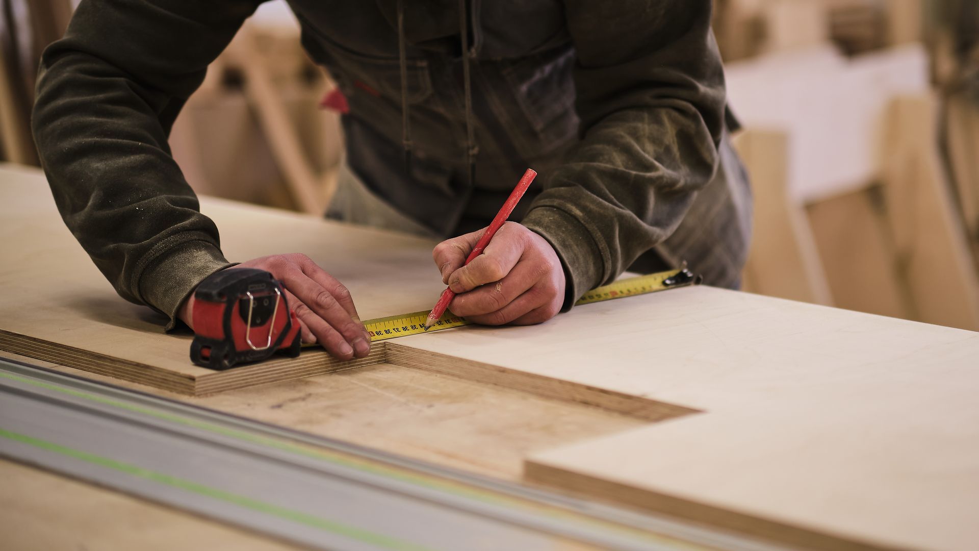 Un menuisier qui prépare un tracé de découpe sur une planche en bois