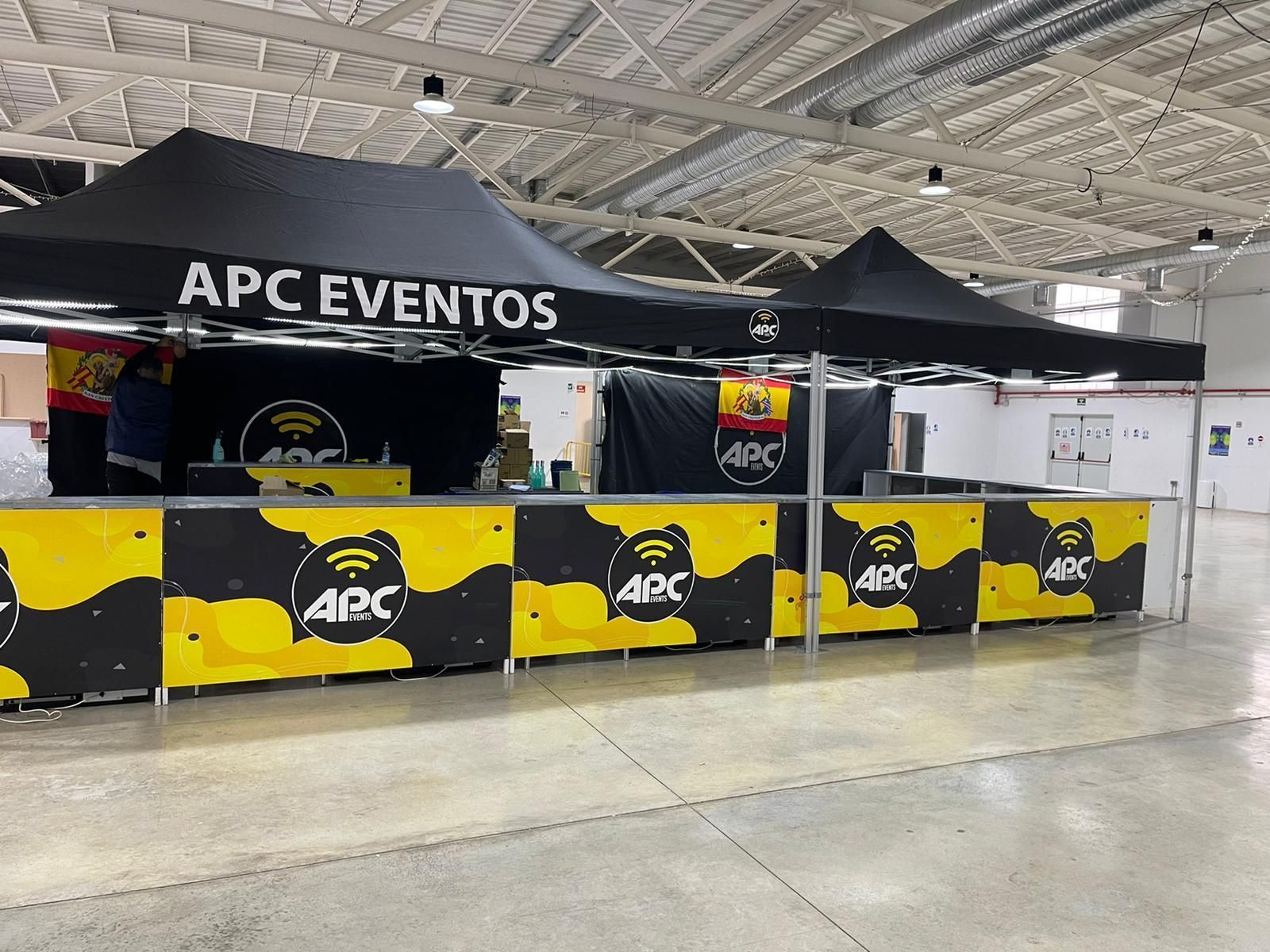 Una fila de mesas bajo una carpa que dice apc eventos