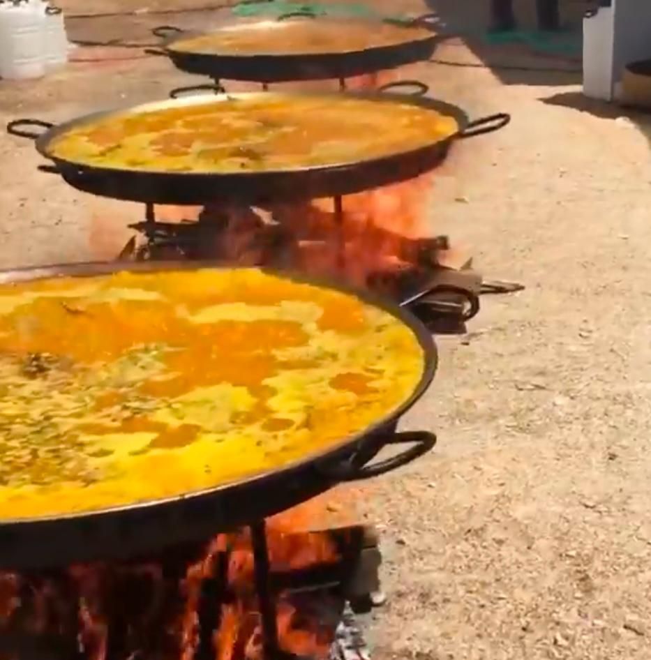 Una fila de sartenes llenas de comida se cocinan sobre el fuego.