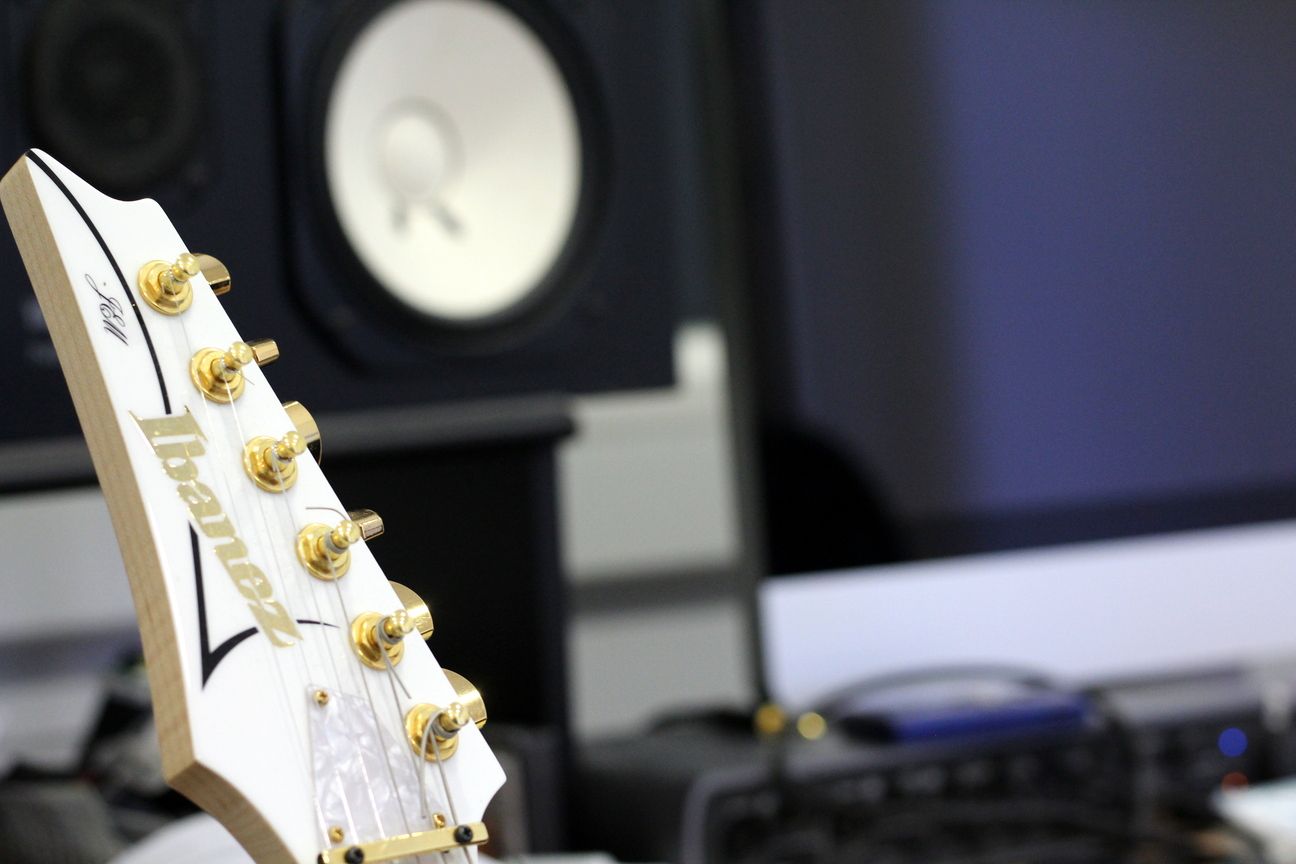 Una guitarra ibanez blanca está delante de un altavoz.