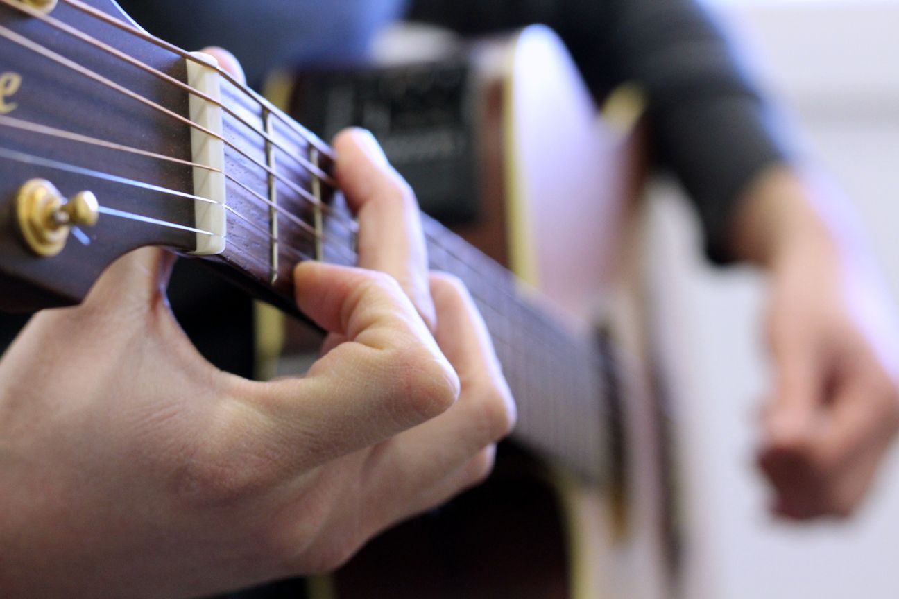 Un primer plano de una persona tocando una guitarra acústica.