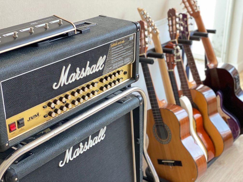Un amplificador de guitarra Marshall está junto a una fila de guitarras.