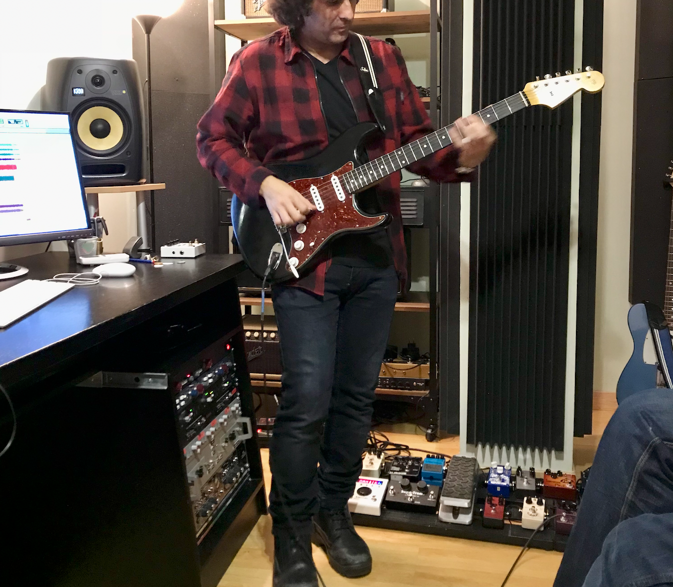 Un hombre con una camisa a cuadros está tocando una guitarra eléctrica.