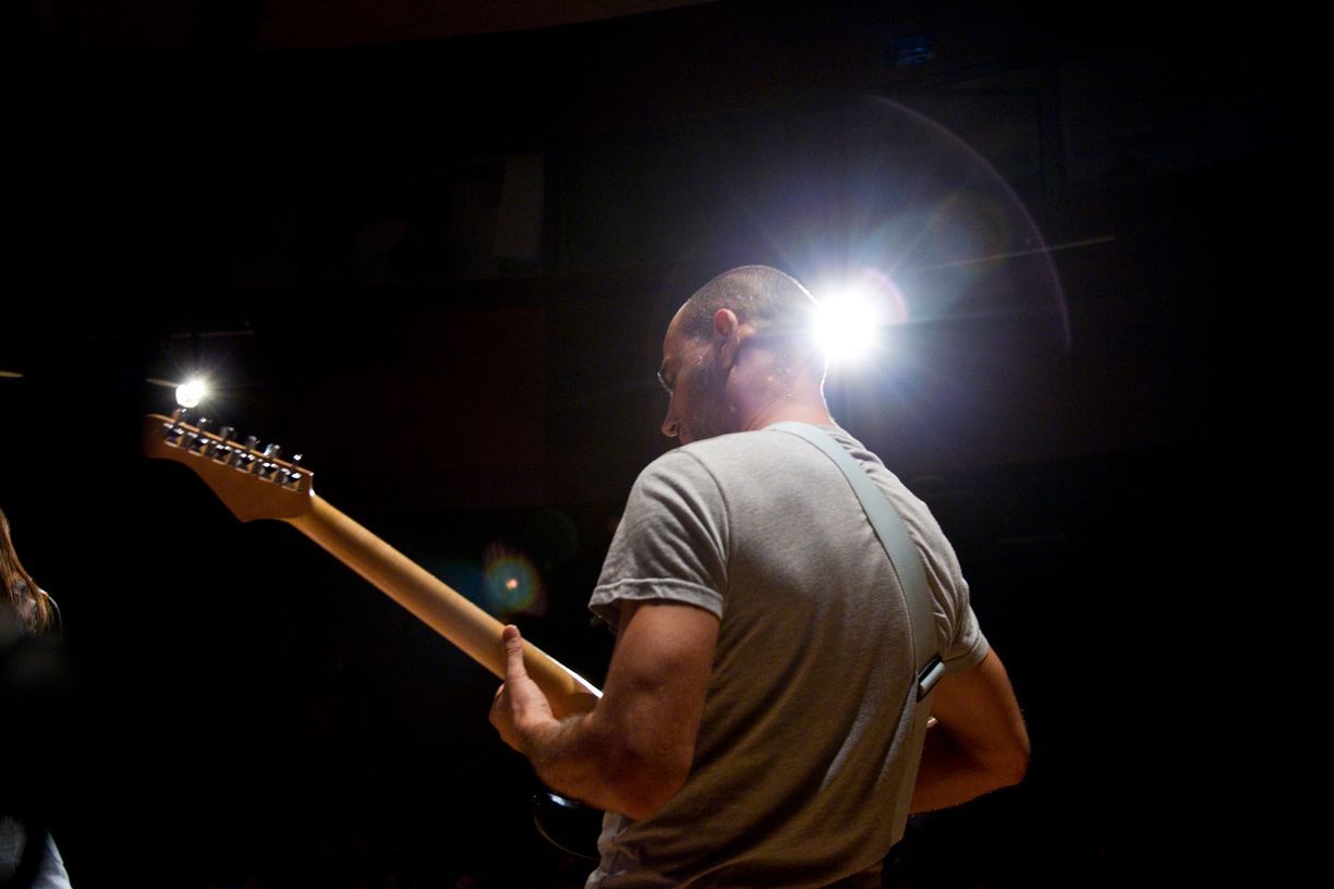 Un hombre está tocando una guitarra eléctrica en una habitación oscura.