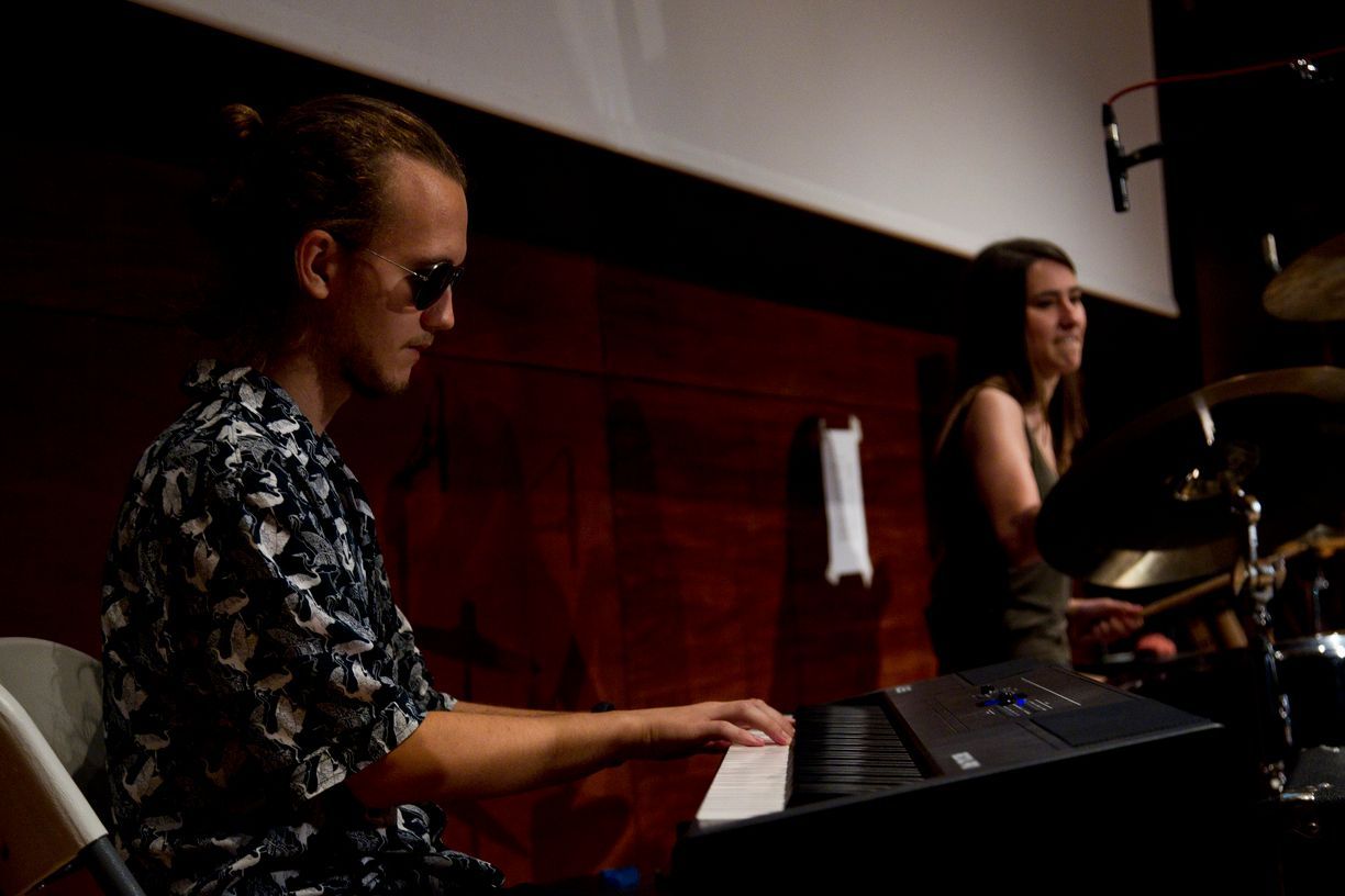 Un hombre y una mujer están tocando el teclado en una habitación oscura.