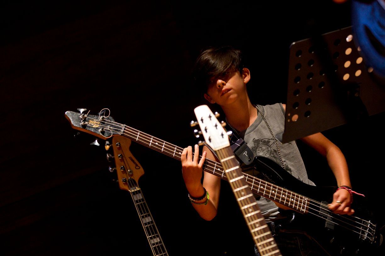 Un niño pequeño está tocando el bajo en una habitación oscura.