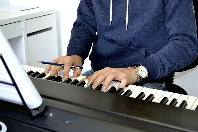 Un hombre está tocando un piano con un lápiz en la mano.
