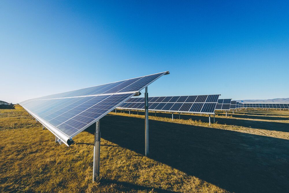 Una fila de paneles solares en un campo con un cielo azul de fondo.