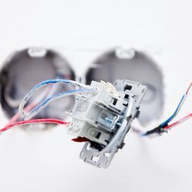 Un primer plano de un interruptor de luz con cables que salen de él.