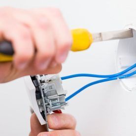 Una persona está arreglando un interruptor de luz con un destornillador.