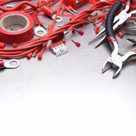 Un montón de cables rojos y herramientas sobre una mesa.