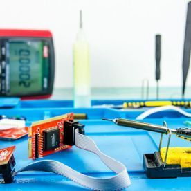 Una caja azul llena de componentes electrónicos y herramientas sobre una mesa.