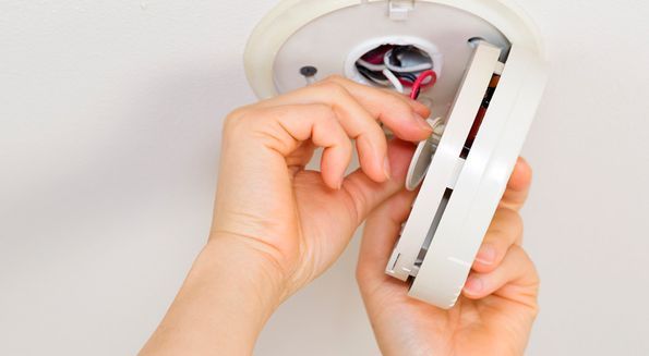 Una persona sostiene un detector de humo en sus manos.