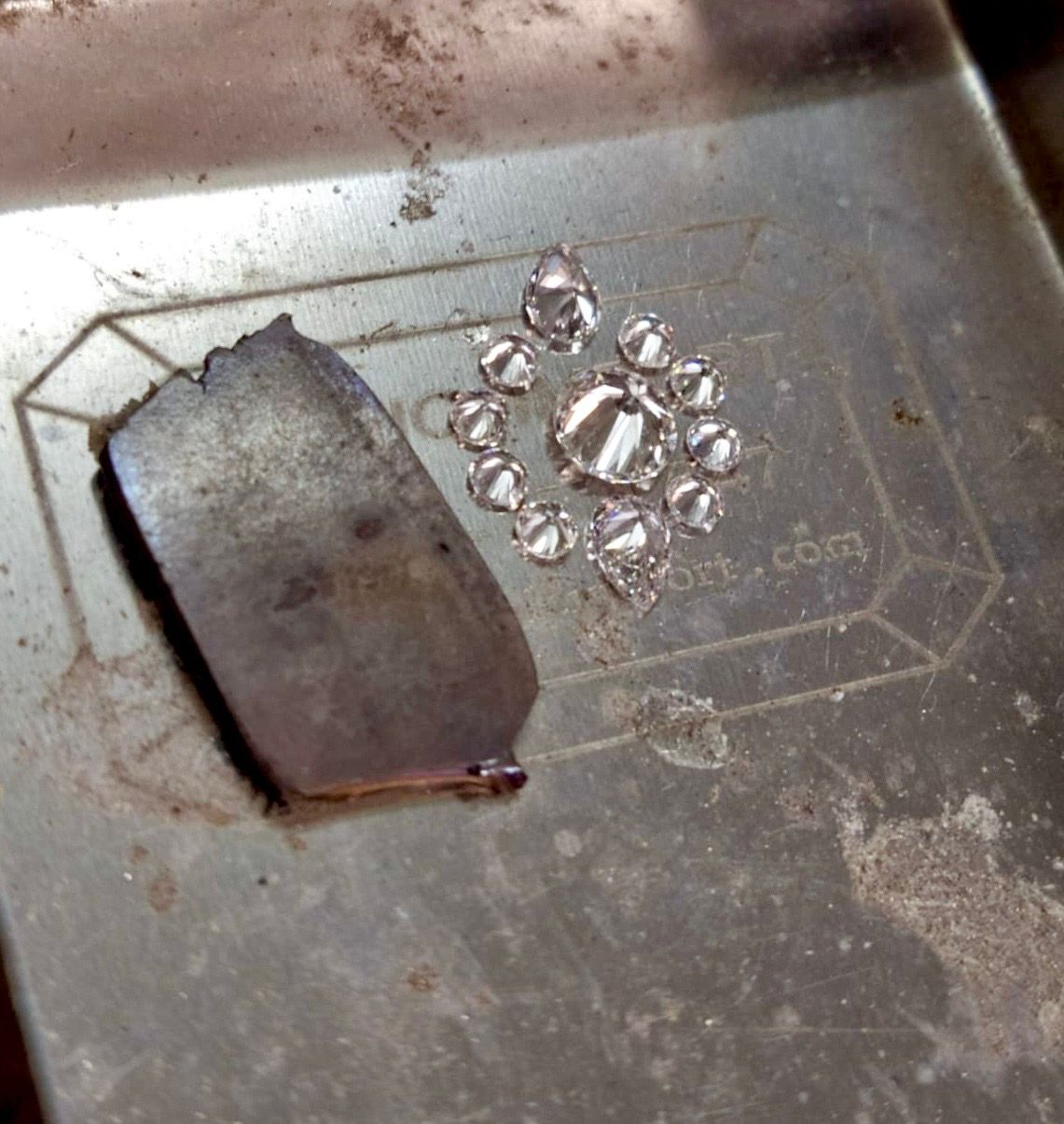 Pendentif en métal endommagé avec de petits cristaux éparpillés sur une surface.