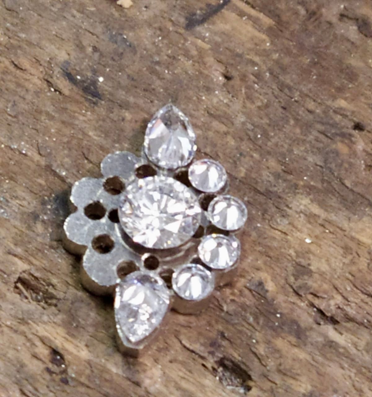 Bijou en forme de fleur avec une grosse pierre centrale et des pierres plus petites tout autour.