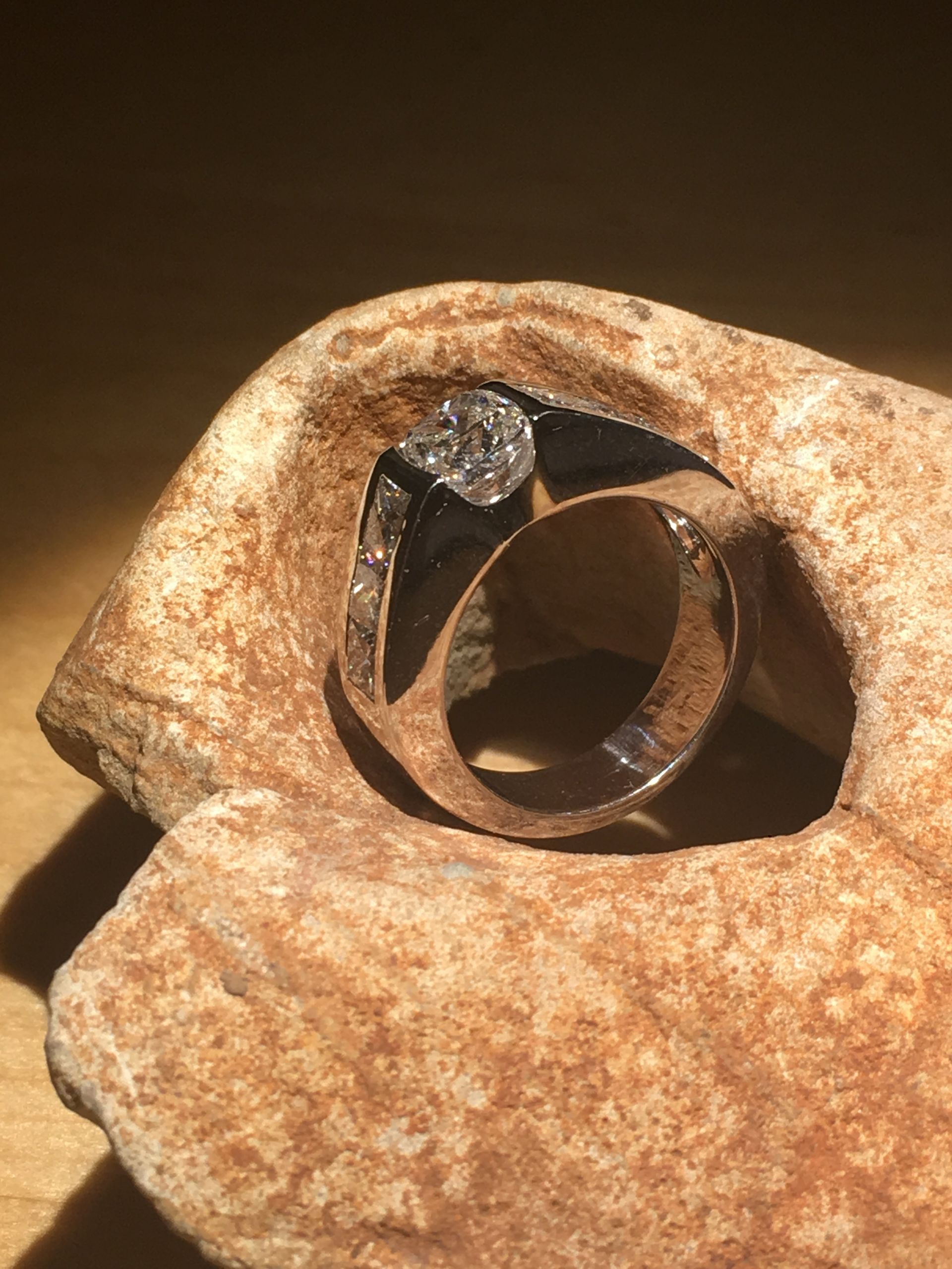 Bague en or avec une grappe de diamants, sertie dans une pierre naturelle, éclairée par la lumière du soleil.