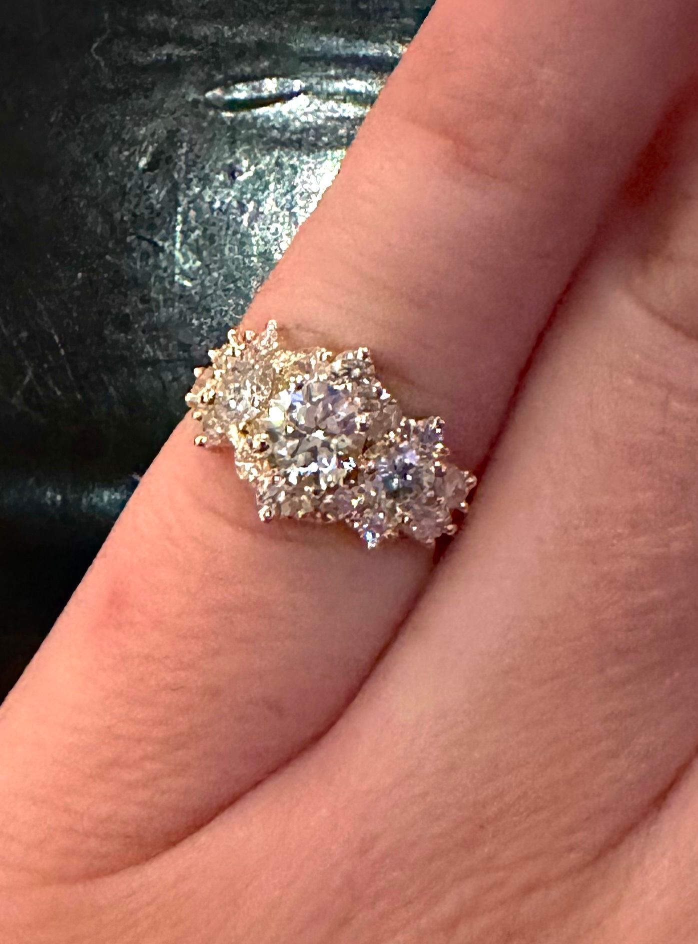 Bague en diamant sur un doigt, sertie de plusieurs pierres de taille rondes, dans une monture en or.