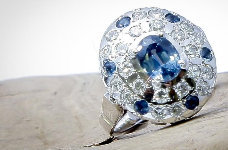 Mains tenant un trèfle à trois feuilles orné de pierres précieuses sur un bloc de bois, en cours de fabrication.