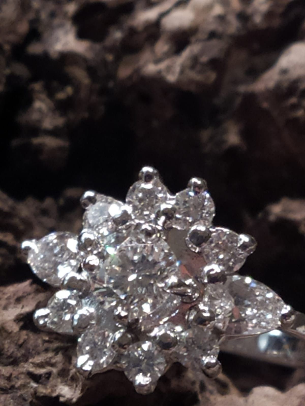 Bague en diamants, design en forme de fleur, sur fond sombre et texturé.