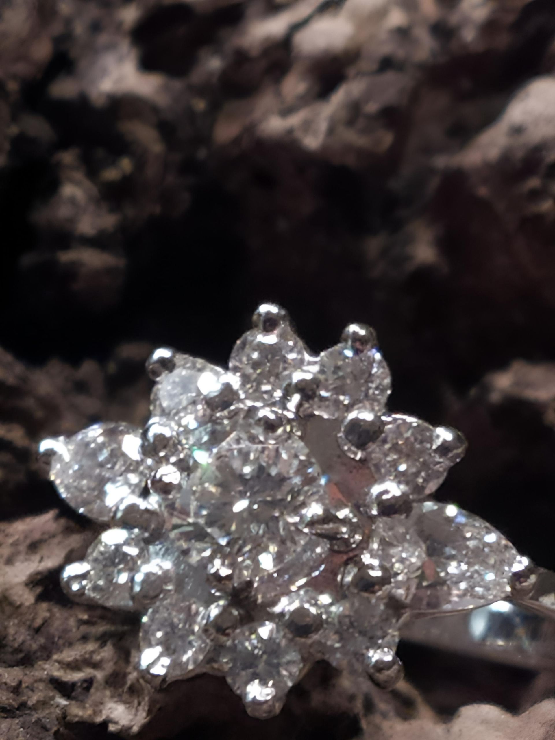 Bague en diamant en forme de fleur, sur une surface en bois texturée.