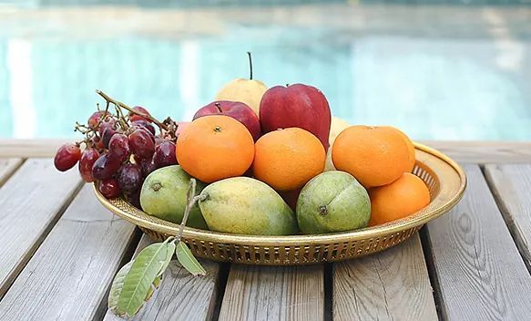 Un bol de fruta está sobre una mesa de madera.