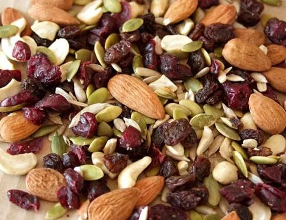 Un montón de frutos secos, incluyendo almendras, arándanos y semillas de calabaza.