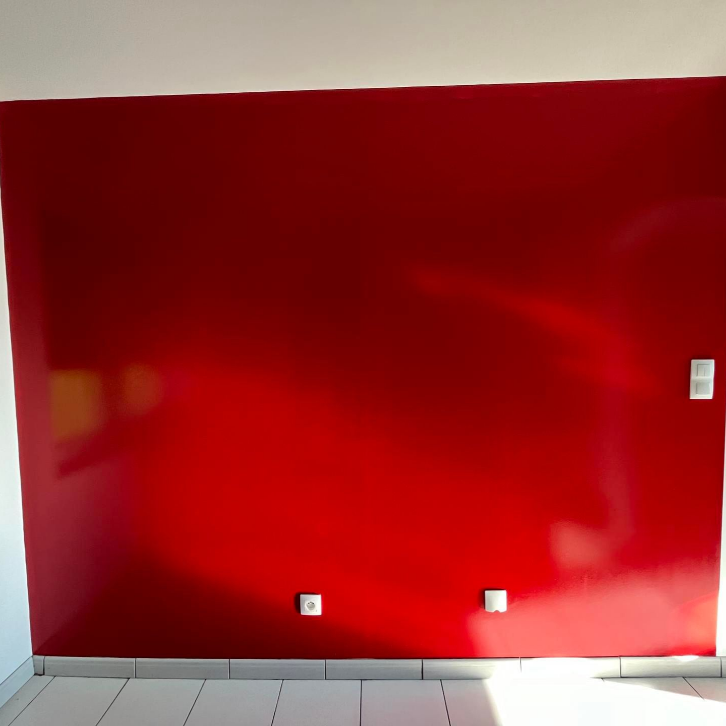 Mur rouge brillant avec trois prises électriques.
