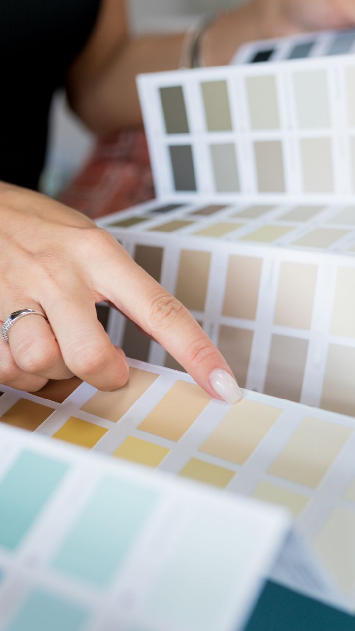 Main pointant du doigt un échantillon de peinture jaune dans un nuancier.