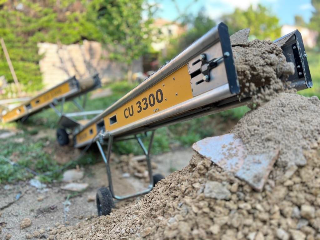 Deux tapis roulants portant l'inscription CU 3300 évacuent les déchets vers l'extérieur.