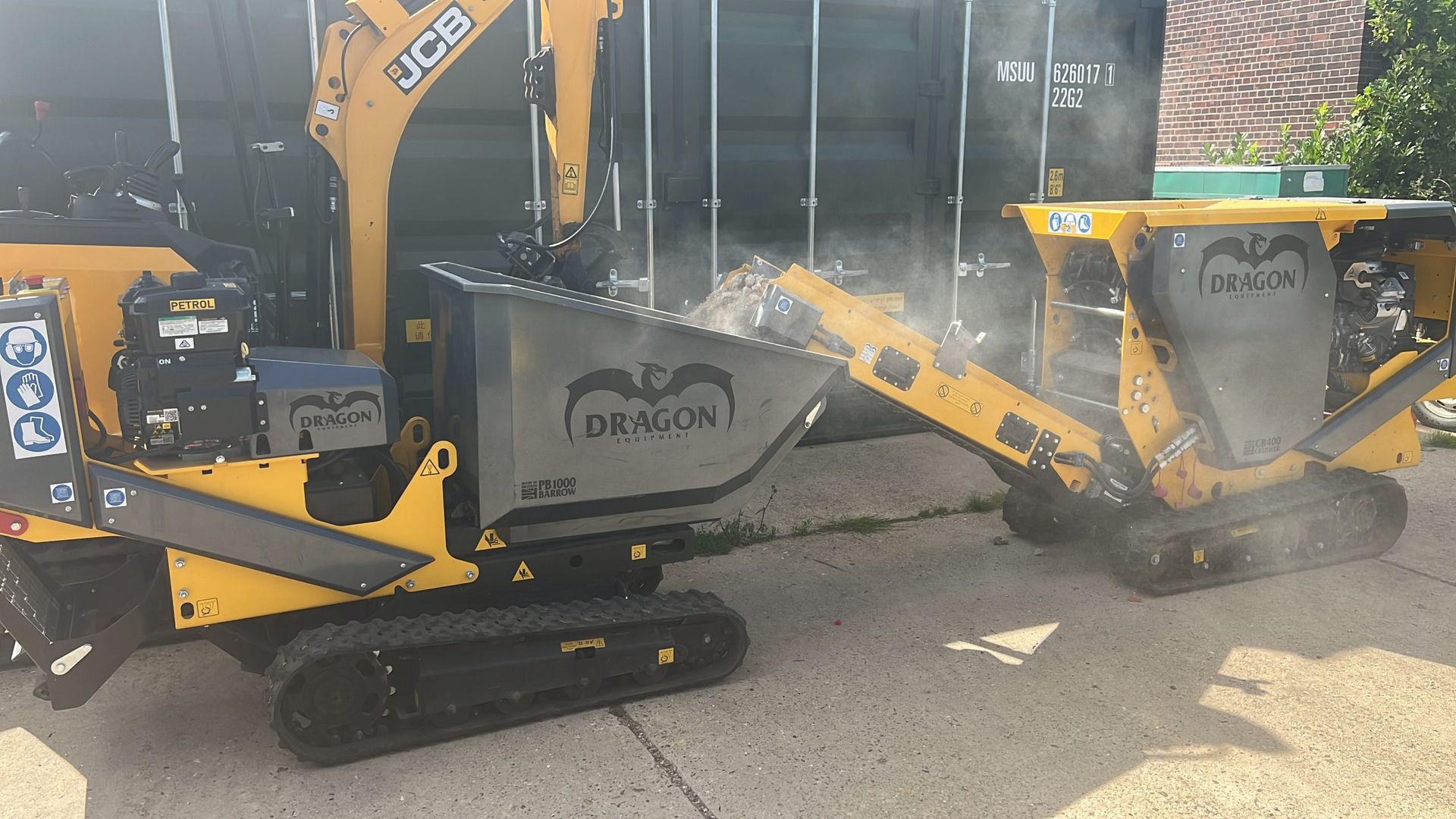 Deux minipelles jaunes broient des débris dans un conteneur, générant de la poussière.