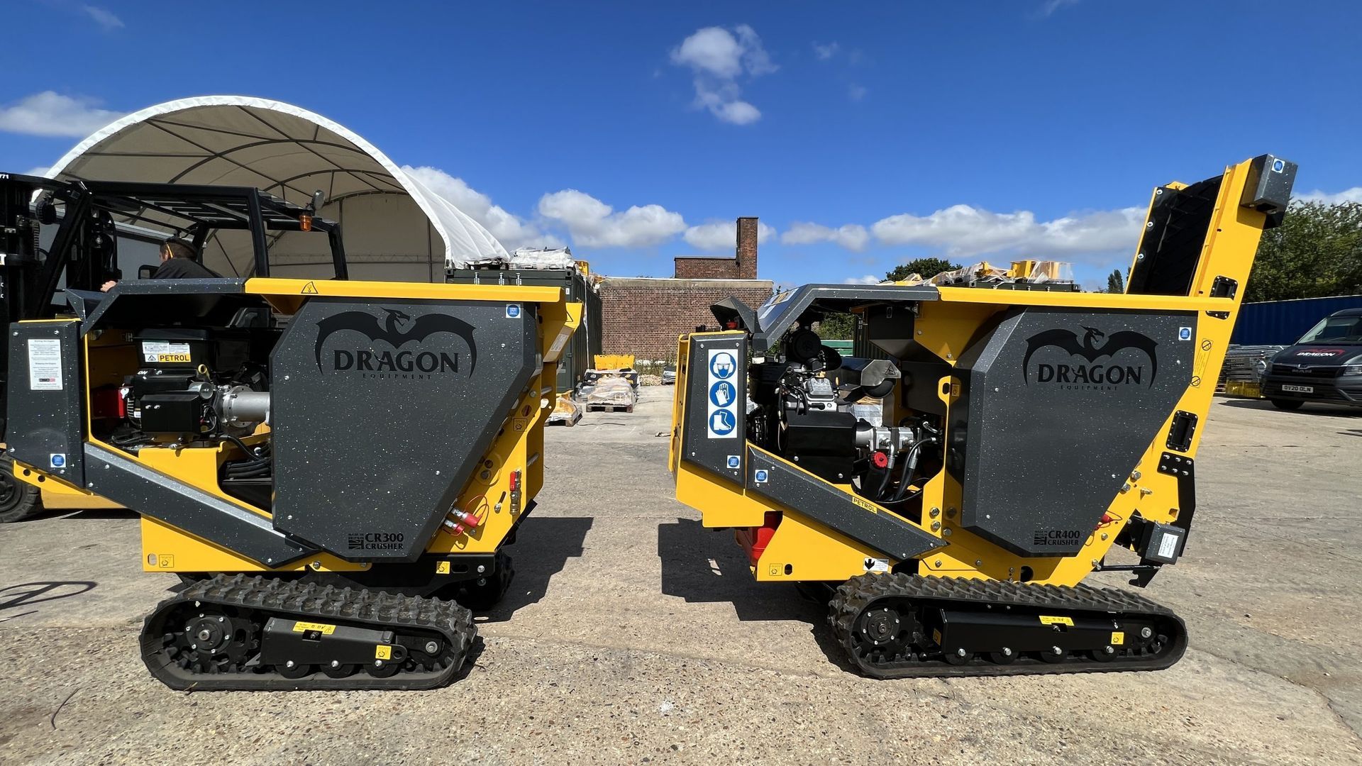 Deux mini-dumpers chenillés jaunes et gris portant le logo BENCON sur une surface en béton, sur fond de ciel bleu.