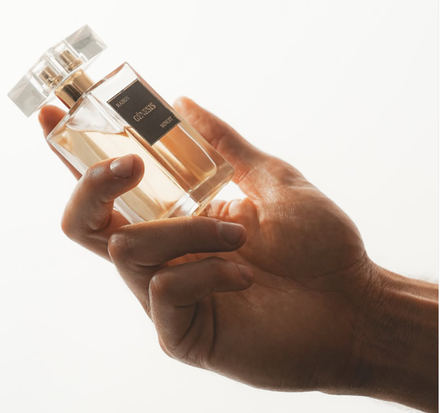 Main tenant un flacon de parfum en verre Maison Genesis.