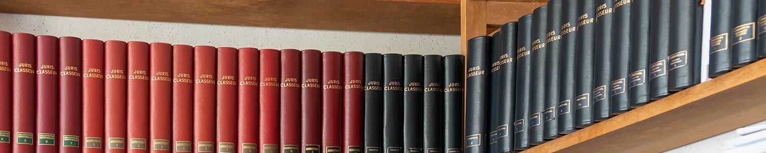Gros plan sur deux étagères en bois remplies d'une collection de livres à couverture rigide rouges et noirs.