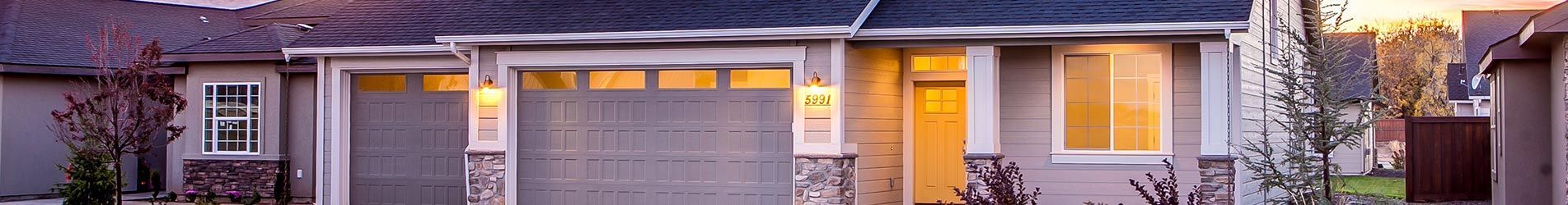 Une maison de banlieue avec un garage double et des éléments en pierre, située dans une rue résidentielle à l'heure dorée.