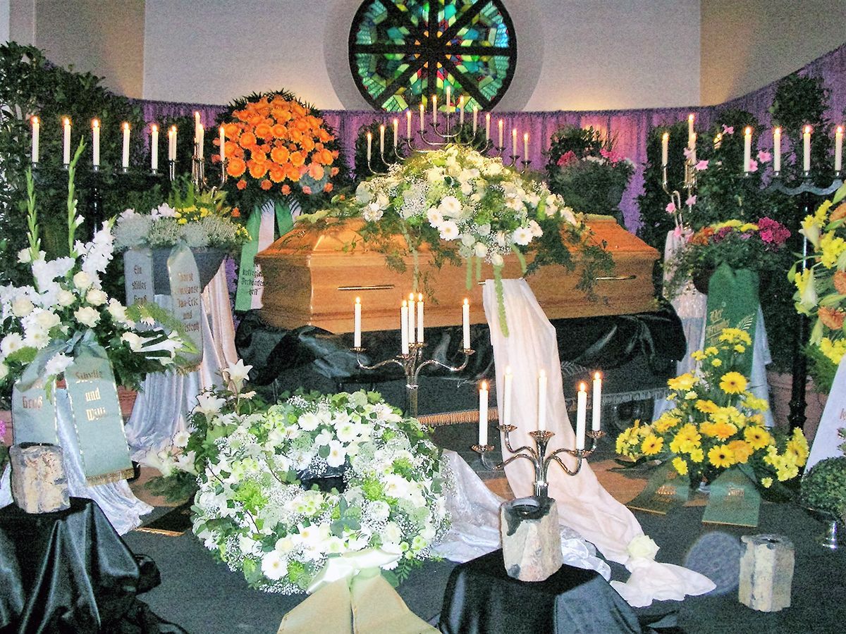 Ein Sarg ist in einer Kirche von Blumen und Kerzen umgeben
