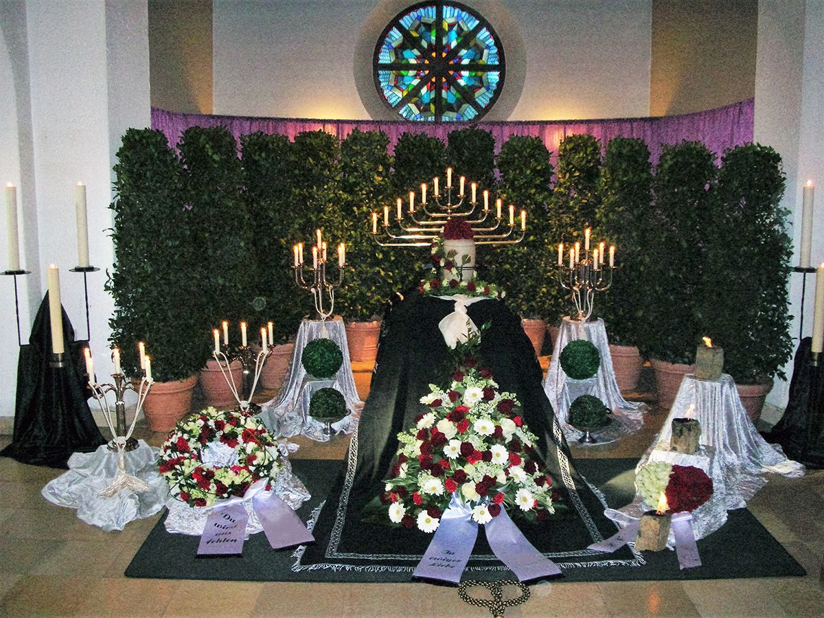 Hinter einer Ausstellung aus Blumen und Kerzen verbirgt sich ein Buntglasfenster