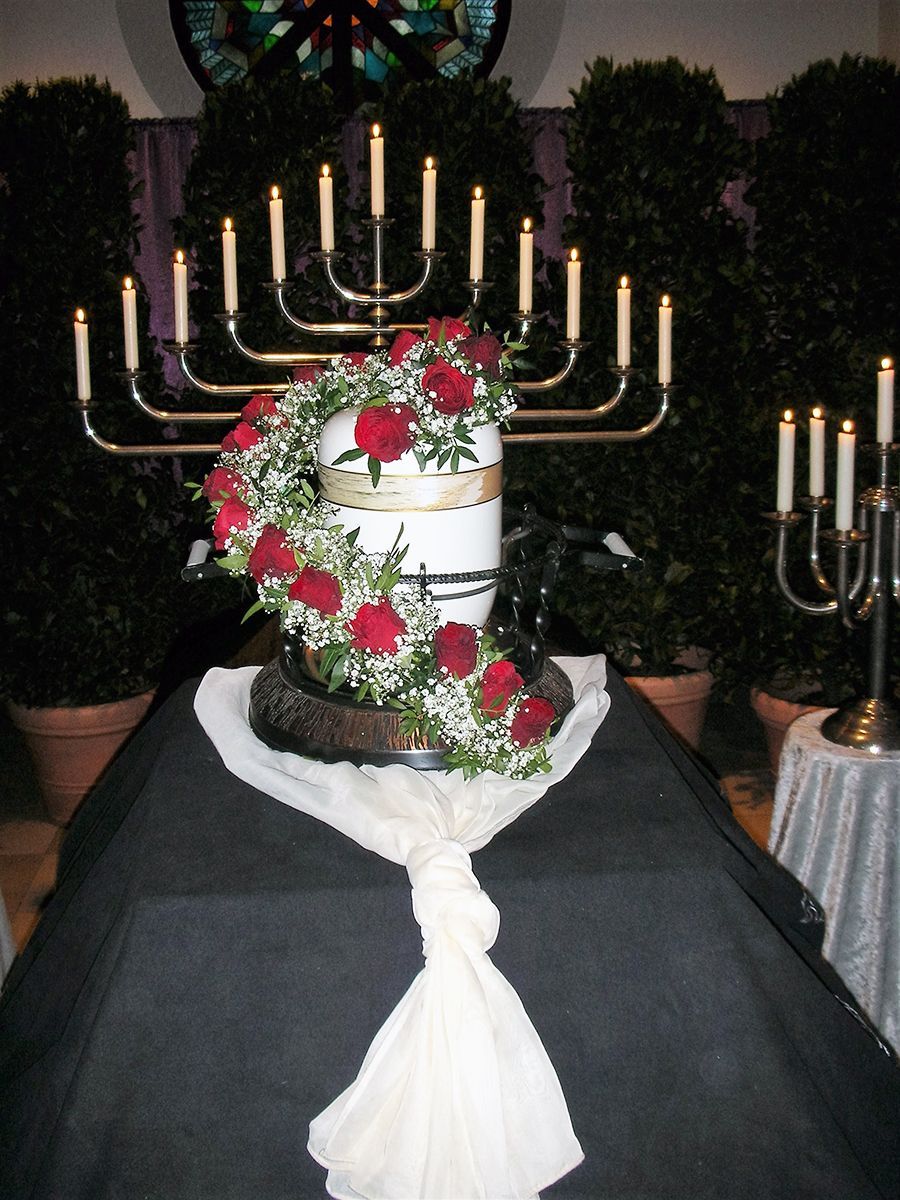 Eine weiße Urne, umgeben von Blumen und Kerzen auf einem Tisch