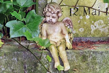 Auf einer Steinmauer sitzt eine Cherub-Statue.