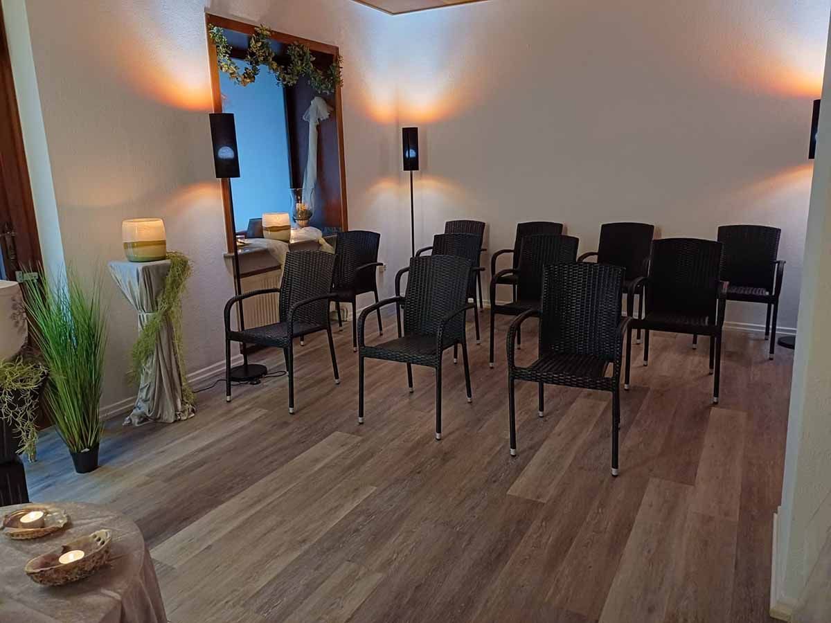 In einem Raum mit Holzboden steht eine Reihe von Stühlen.