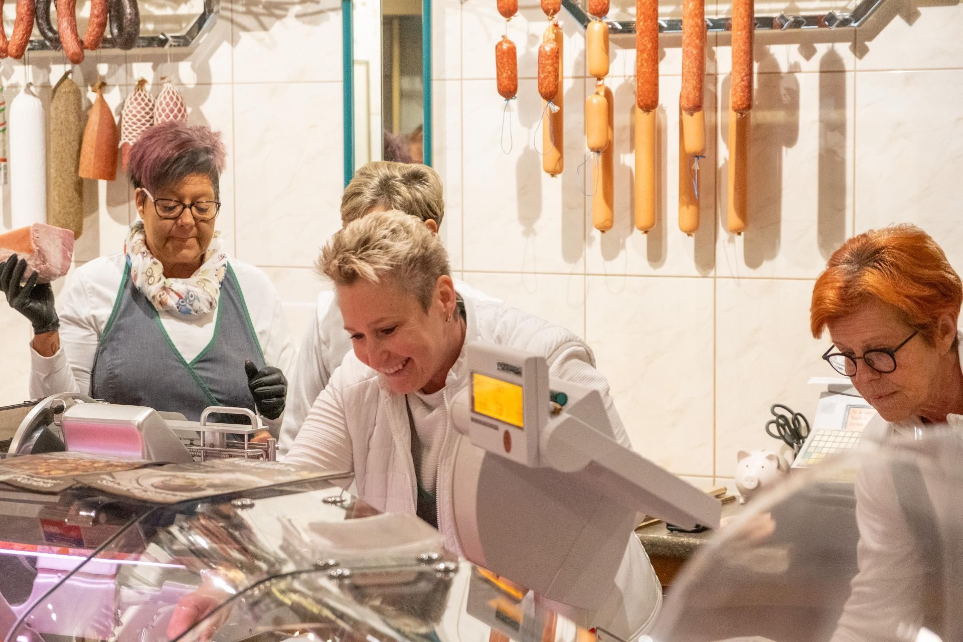 Metzgerei-Team bei der Arbeit an der Fleischtheke mit frischen Wurst- und Fleischwaren