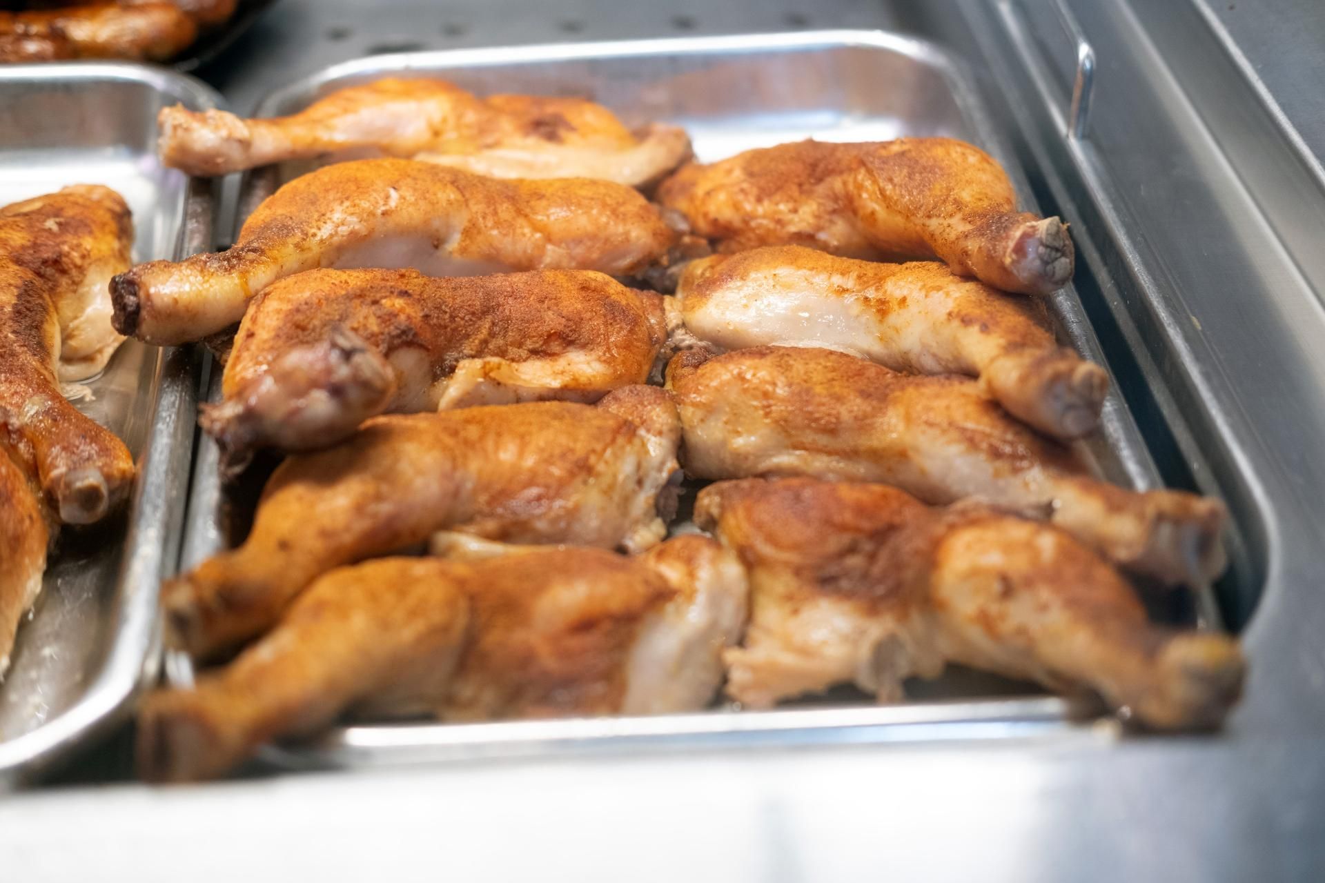 Goldbraune Grillhähnchen frisch zubereitet in der warmen Theke