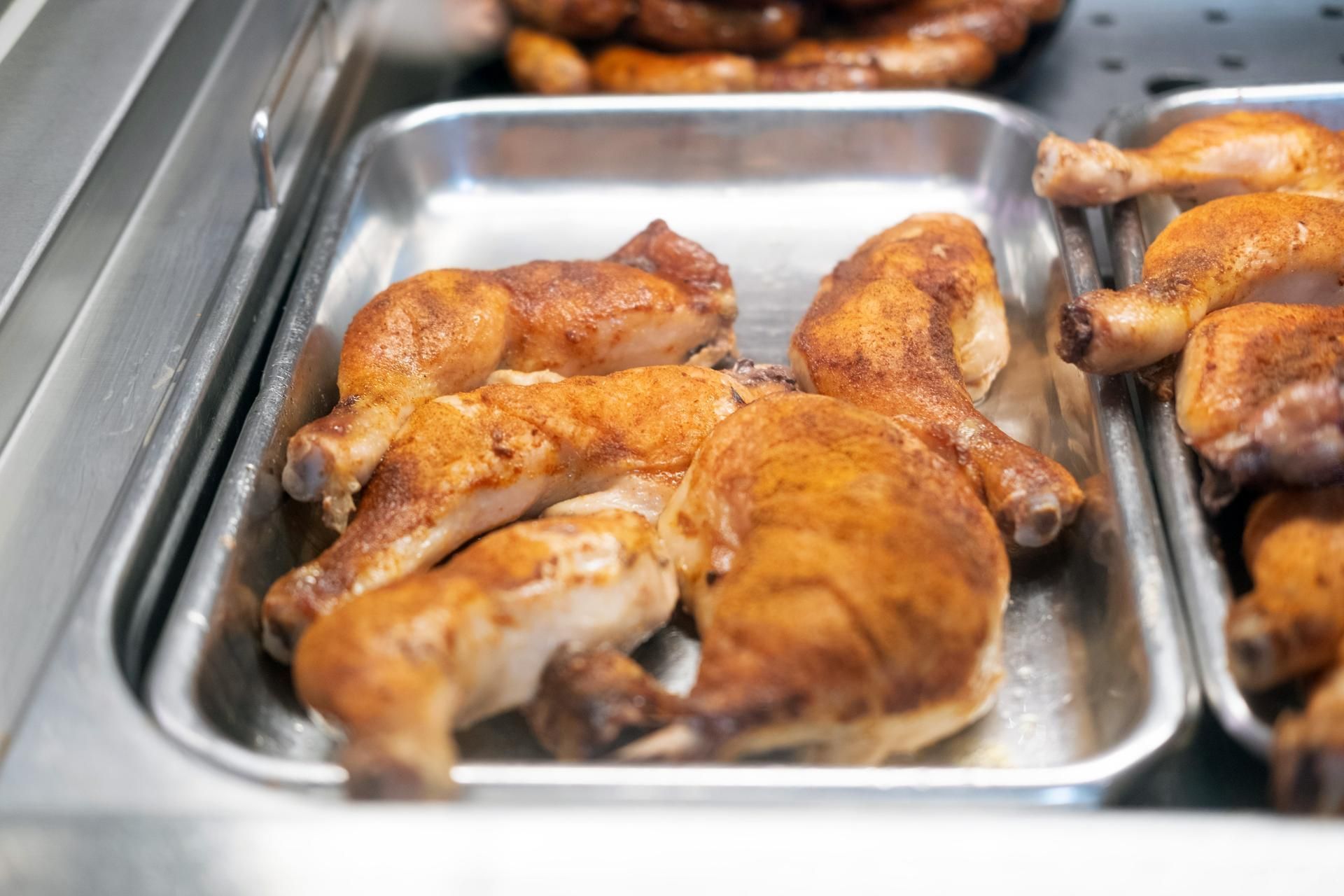 Goldbraune Grillhähnchen frisch zubereitet in der warmen Theke der Metzgerei