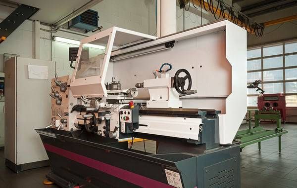 Eine weiss-violette Industriedrehmaschine in einer Werkstattumgebung.