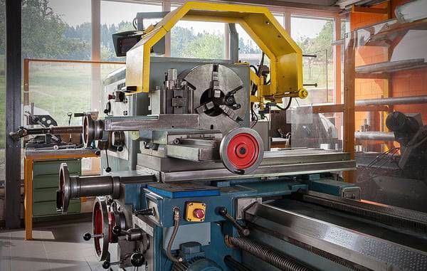 Drehmaschine in einer Werkstatt, Metallbearbeitungsgerät mit gelber Schutzvorrichtung.
