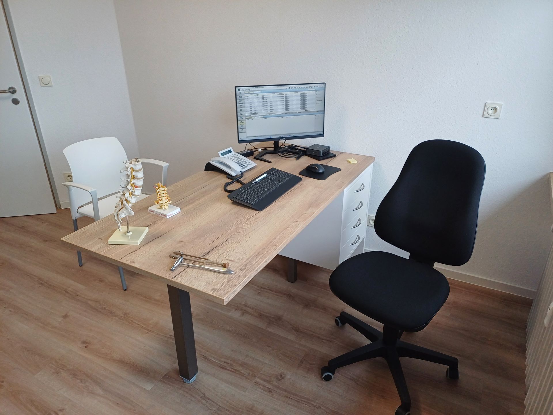 Ein Schreibtisch mit einem Computer und einem Stuhl in einem Zimmer