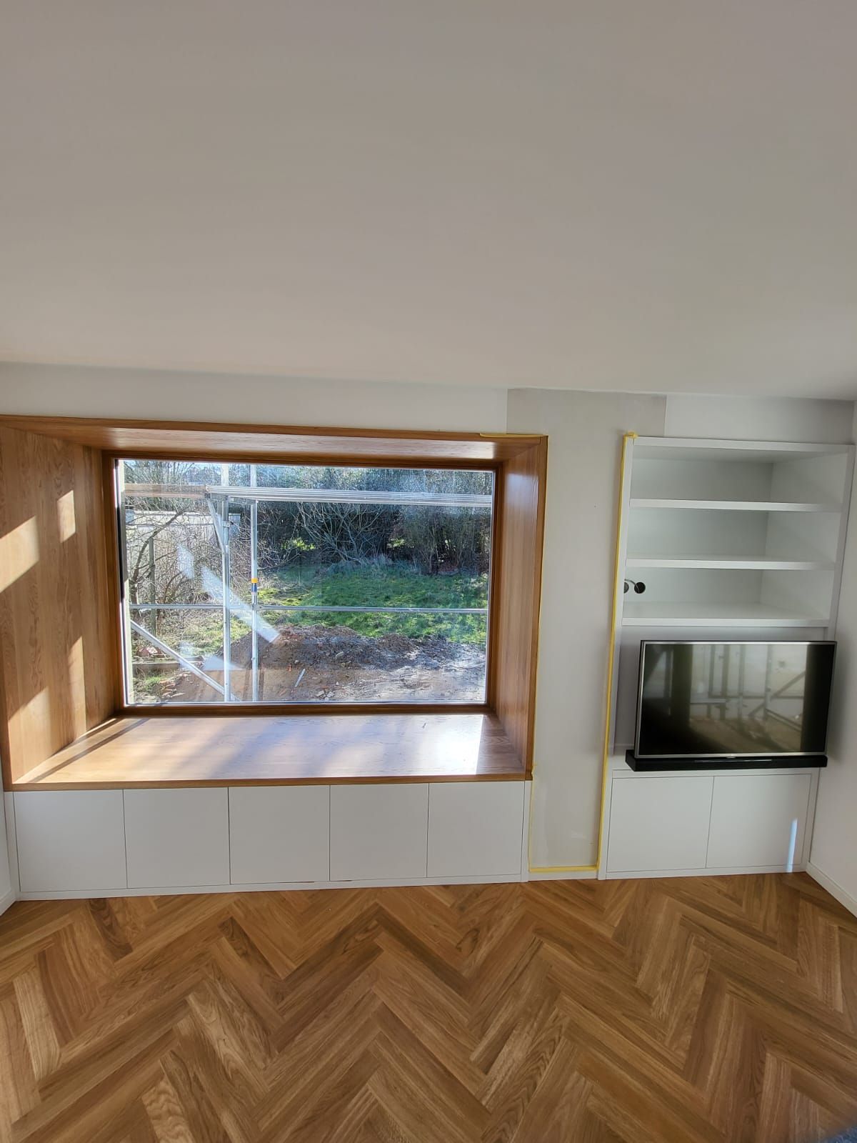 Ein Wohnzimmer mit großem Fenster und Holzboden