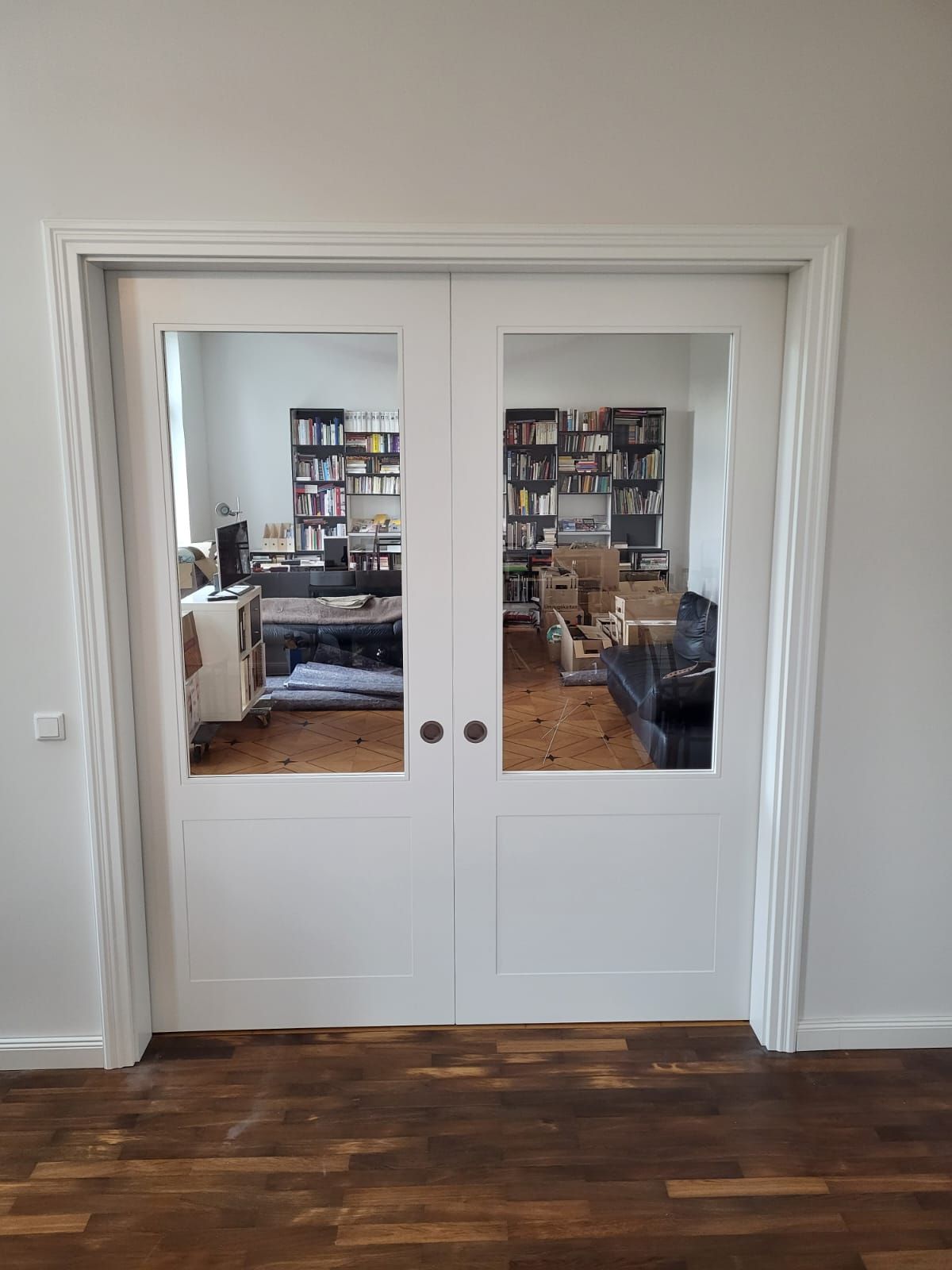 Ein Wohnzimmer mit Glasschiebetüren, die zu einer Bibliothek führen.